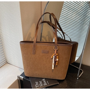 Detail of vintage matte suede tote bag featuring ethnic wooden bead pendant and long straps