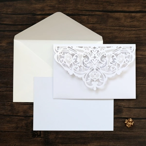 Detailed laser-cut lace wedding invitation with inner card and envelope on wood