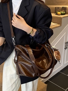 Large dark brown tote bag with glossy finish and plush donut pendant on shoulder strap