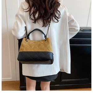 Detail of a dual-color bucket bag with quilted leather and elegant gold chain strap