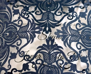 Navy blue laser-cut wedding invitation cover with elegant damask floral pattern