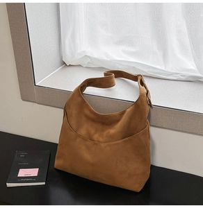 Détail d'un sac hobo en daim marron avec coutures et bandoulière réglable