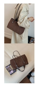 Large brown suede tote bag featuring a chain shoulder strap and leather handles shown on model
