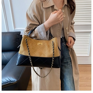 Detail of quilted leather and suede bucket bag featuring a gold chain strap and lock