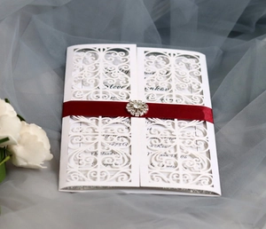 Détail d'invitation de mariage découpée au laser avec ruban satin rouge et strass