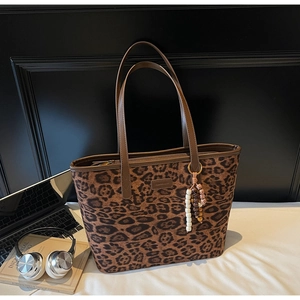 Detail of leopard print tote bag with brown straps and beaded tassel charm accessory