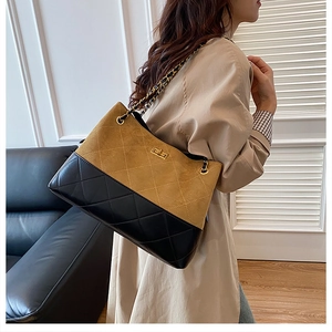 Detail of a quilted tote bag featuring khaki suede and black leather with a gold chain strap