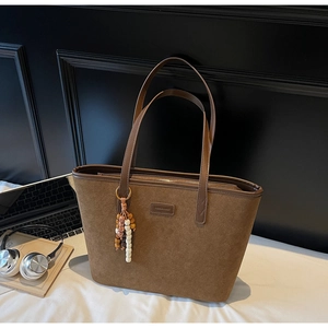 Detail of dark brown frosted leather tote bag with colorful beaded tassel pendant