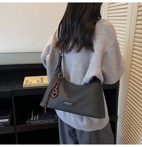 Detail view of a charcoal grey hobo bag featuring logo patch and woven cord accessory