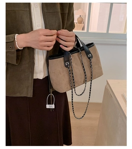 Detail of suede bucket bag with chain strap and leather handle in autumn style