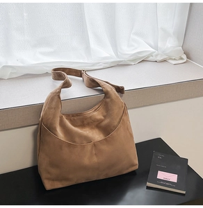 Détail de la texture d'un sac hobo en daim marron avec coutures et bandoulière