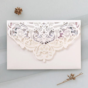 Detail of laser-cut lace invitation card with floral patterns and cream white envelope