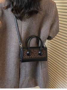 Chic black leather handbag with brown leopard print panel and adjustable crossbody strap
