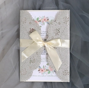 Detail of laser cut silver glitter rose invitation with cream ribbon and floral insert
