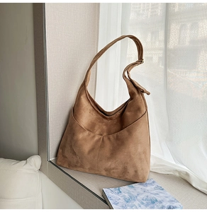 Détail du sac hobo en daim marron avec poche avant rétro et texture douce haut de gamme