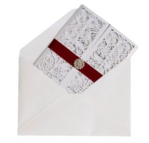Détail d'invitation de mariage découpée au laser avec ruban bordeaux et boucle strass