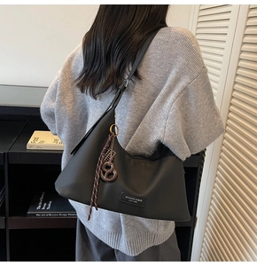 Close-up of black matte hobo bag with a brown woven rope charm and adjustable strap