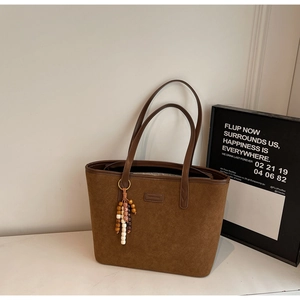 Detail of vintage matte brown suede tote bag with leather handles and wooden bead charm