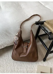 Vue détaillée du sac à bandoulière marron vintage avec texture grainée et pompon en peluche