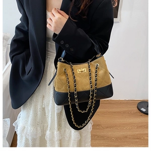 Detail of two-tone quilted shoulder bag with gold chain strap worn by a model