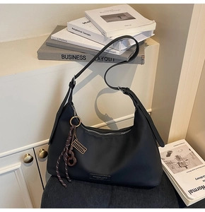 Detailed shot of black crescent shoulder bag with silver zipper and gold abacus charm