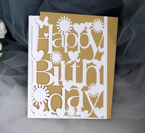 Macro view of laser-cut Happy Birthday card with intricate sunflower and heart patterns