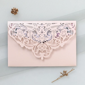Detailed laser-cut floral pattern on pink wedding invitation envelope with insert card