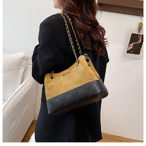 Detail view of two-tone quilted leather bucket bag with chain strap worn by a model