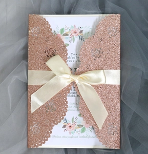 Detail of rose gold laser cut floral wedding invitation with watercolor card and ribbon
