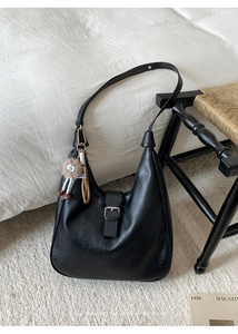 Détail d'un sac hobo en similicuir noir avec boucle argentée et charm en peluche