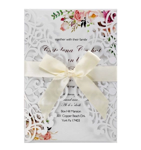 Detailed laser cut floral wedding invitation with pink flowers and a white satin ribbon bow