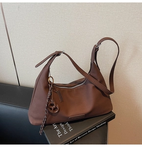Detail of coffee brown leather bag with heart knot charm and silver metal zipper