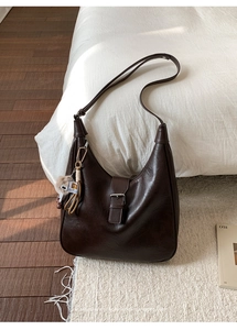 Détail du sac bandoulière marron foncé en simili cuir avec boucle et breloque peluche