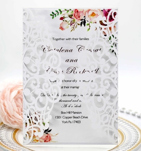 Detail of laser-cut white wedding invitation with floral printed insert and rose decor
