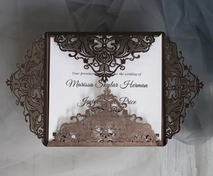 Macro detail of laser cut floral wedding invitation with brown cover and white inner card