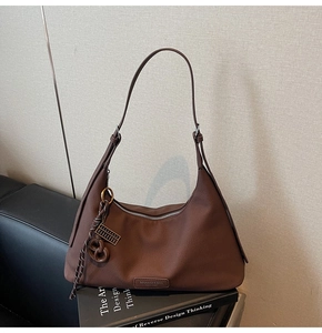 Detail of dark brown leather hobo bag with logo plate and decorative abacus charm