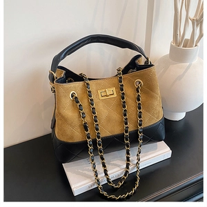 Detail of mixed-material bucket bag with gold turn-lock and chain strap on books