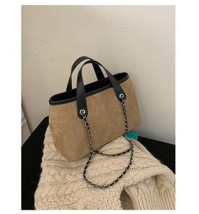 Detail of brown suede bucket bag with black leather trim and chain strap on sweater