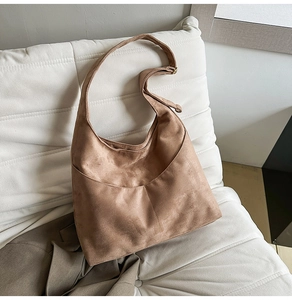Détail d'un sac hobo en daim marron avec poche extérieure incurvée et large bandoulière
