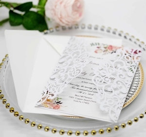 Detail of laser-cut wedding invitation with pink floral insert on an elegant plate