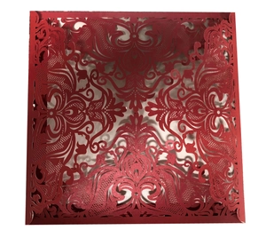 Detailed laser-cut pattern on a red wedding invitation card with intricate floral design