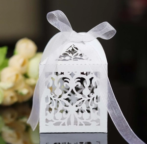 Detail of white laser-cut gift box with floral patterns and a satin ribbon bow