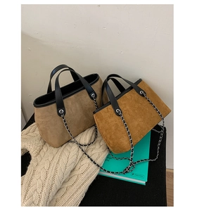 Close-up of suede tote bags in beige and caramel with silver chain straps and black handles