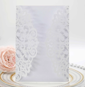 Detailed laser-cut white pearlescent paper invitation with ornate floral patterns