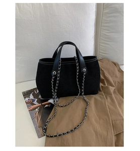 Detail of the black suede bucket bag with silver chain strap on a stylish sofa