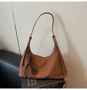 Detail of lychee textured brown leather hobo bag with silver zipper and brand tag