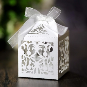 Close-up of white laser-cut candy box with European lace patterns and a silk ribbon bow