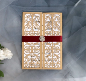 Detail showing the champagne gold hollow lace invitation card with a red satin ribbon