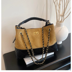 Close-up of diamond quilted black leather and tan suede with golden metal twist lock