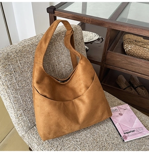 Détail du sac hobo en daim marron foncé avec surpiqûres premium sur un canapé moelleux